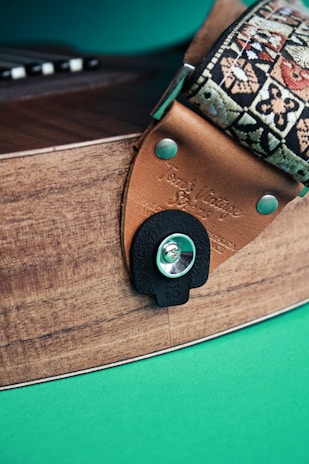 Close-up of a worn leather guitar strap hanging on a rustic wooden wall.