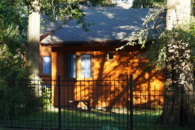 Compact wooden accommodation wendy house with a small porch and curtains.