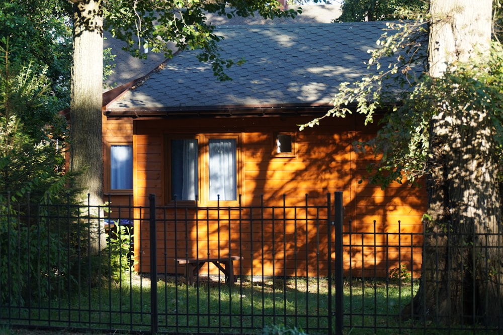 brown wooden house near green tree during daytime