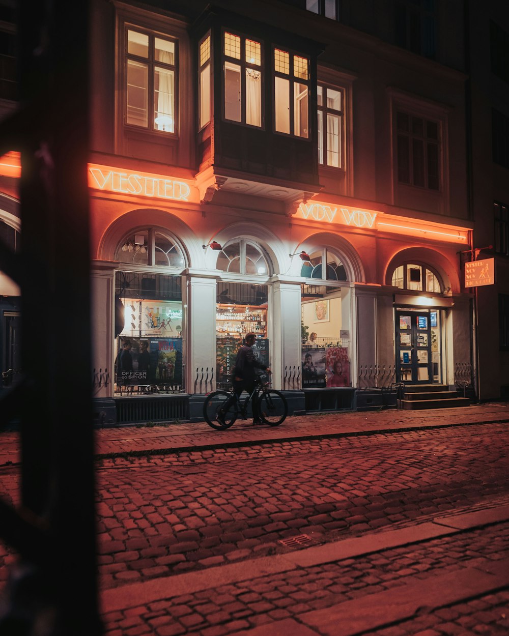 夜間、茶色のコンクリートの建物の脇に停車している黒い自転車
