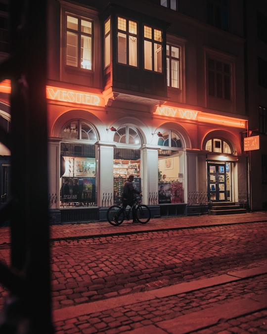 black bicycle parked beside brown concrete building during night time in Cafébiografen Vester Vov Vov Denmark