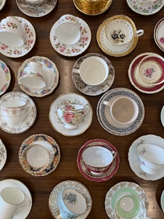 An assortment of colorful tea cups and pots arranged on a rustic wooden tray