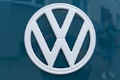 A Volkswagen logo in white is prominently displayed against a dark teal background.