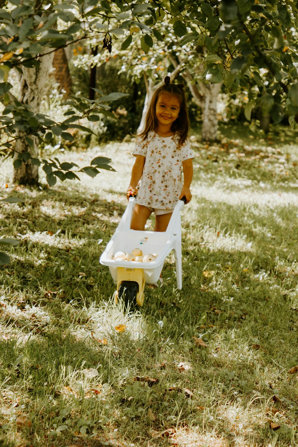 girl in yellow and white floral dress sitting on white plastic chair on green grass during