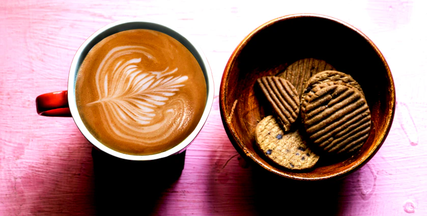 A warm, inviting coffee cup surrounded by fresh ingredients like tea leaves, waffle pieces, and colorful ice cream scoops.