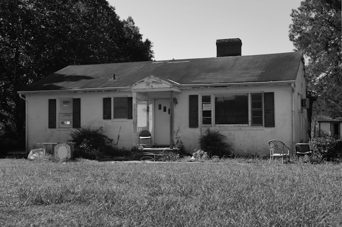 A vacant two story house photographed in grayscale, representing a home in the foreclosure process