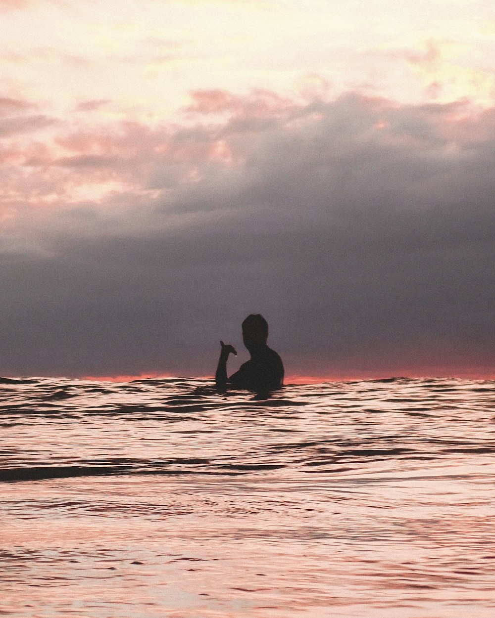 silhouette of man surfing on sea during sunset