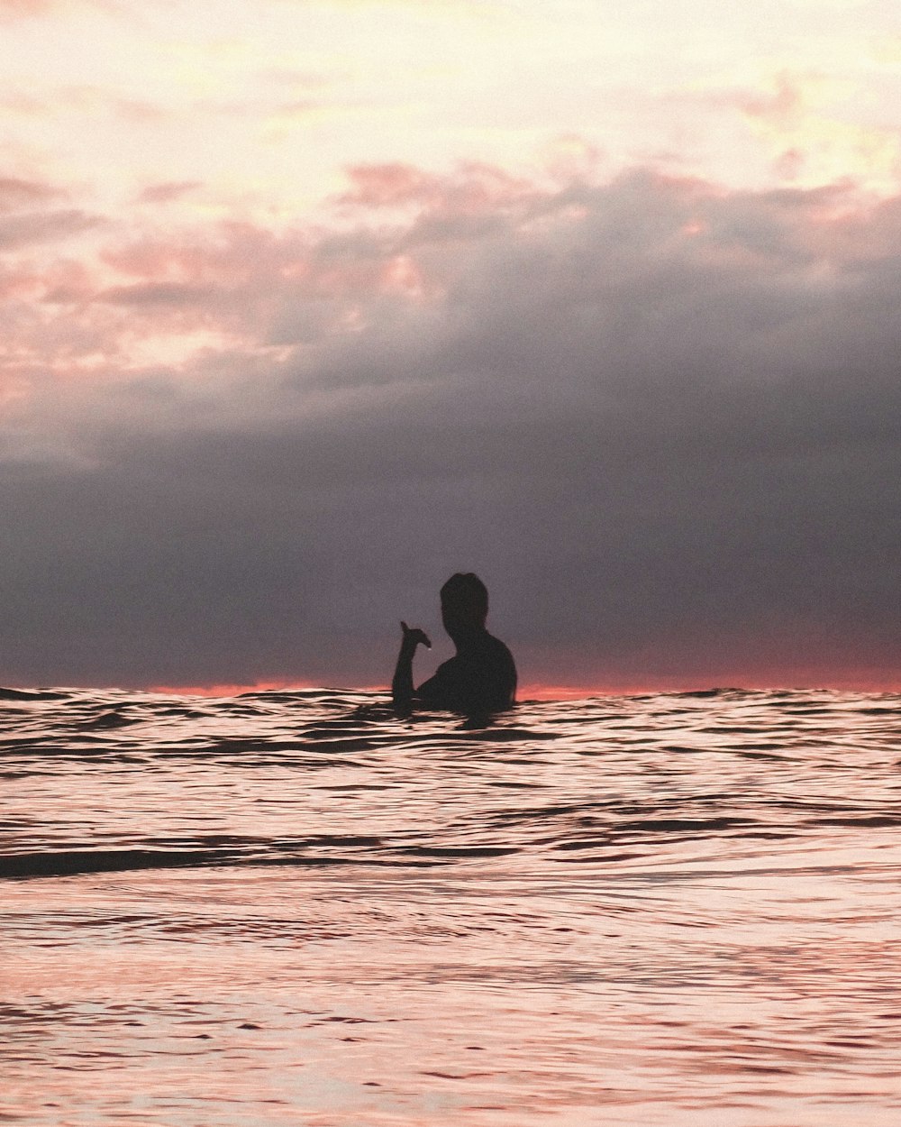 Silueta del hombre surfeando en el mar durante la puesta del sol