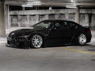 Sporty car wrapped in matte black vinyl parked under soft lighting.
