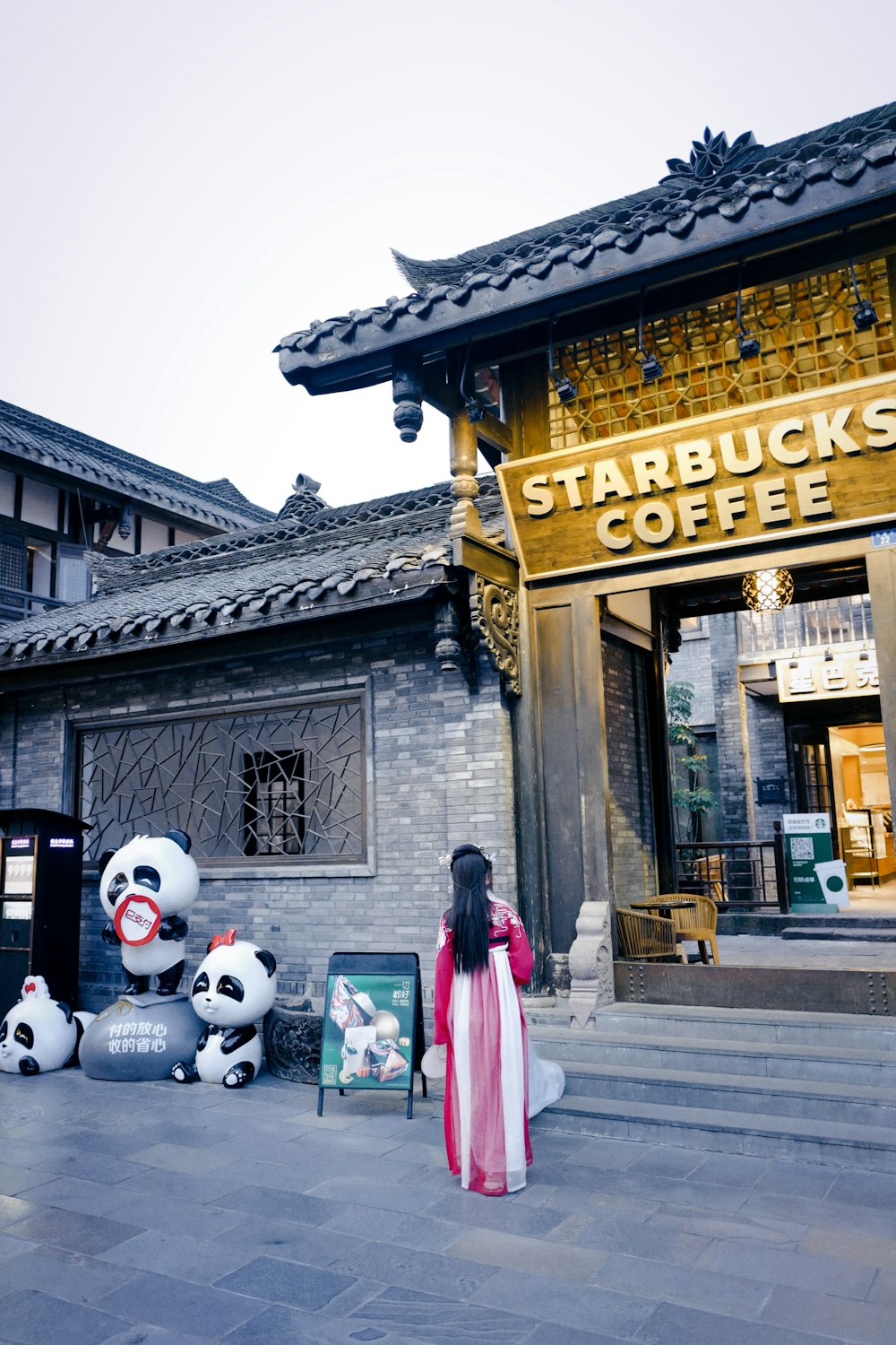 woman in red and blue dress standing beside white panda plush toy