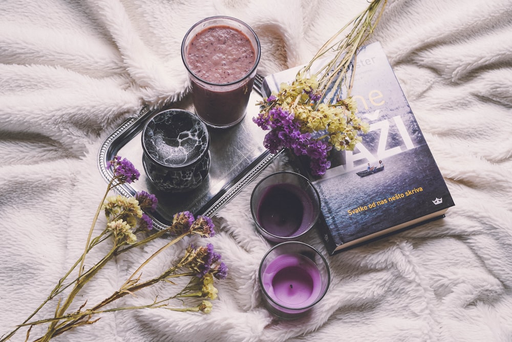 purple flowers beside black and silver camera lens on white textile