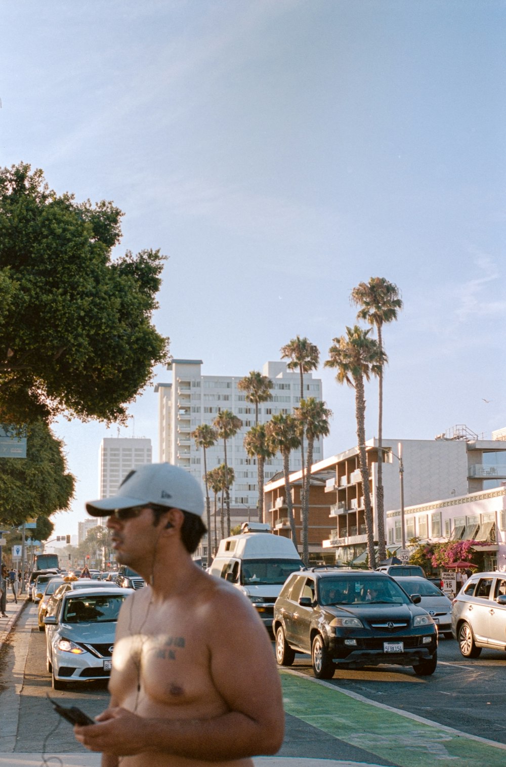 Hombre con sombrero blanco de pie cerca de los coches durante el día