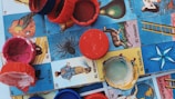Colorful plastic bottle caps are scattered on a Mexican Lotería board, featuring various illustrated cards with vibrant imagery and Spanish text.