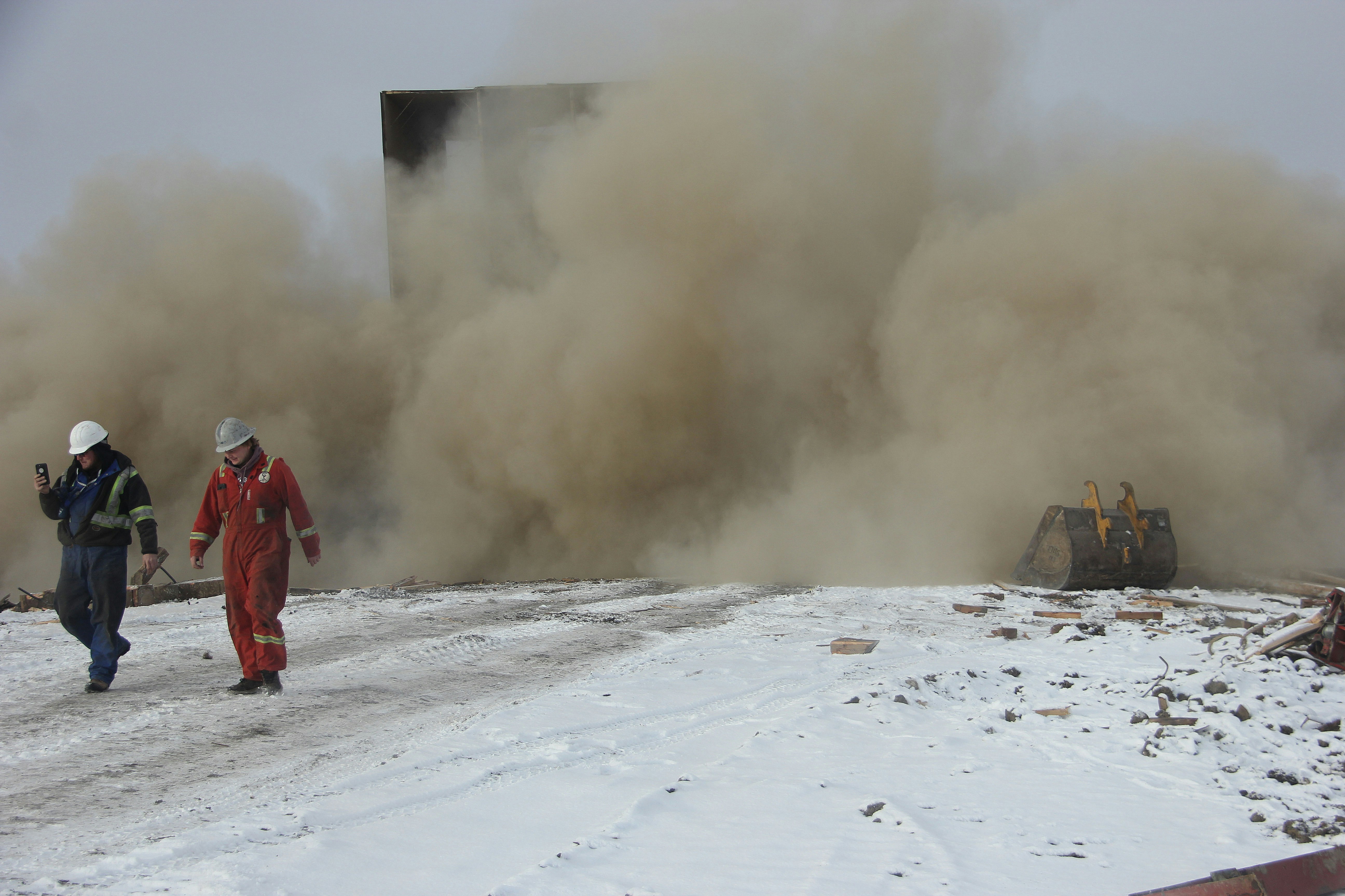man in red jacket walking on snow covered ground during daytime