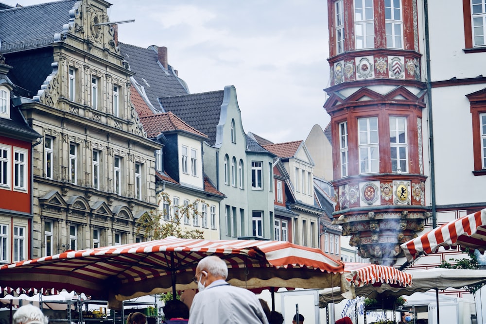 man in white shirt sitting on red and brown umbrella