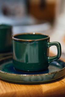 Elegant black espresso cup with emerald green saucer on matte black surface