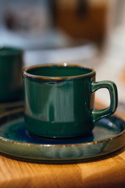 Elegant black espresso cup with emerald green saucer on matte black surface