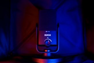 A microphone with a prominent brand logo and volume control knob, illuminated by dramatic red and blue lighting, creating a visually striking contrast.