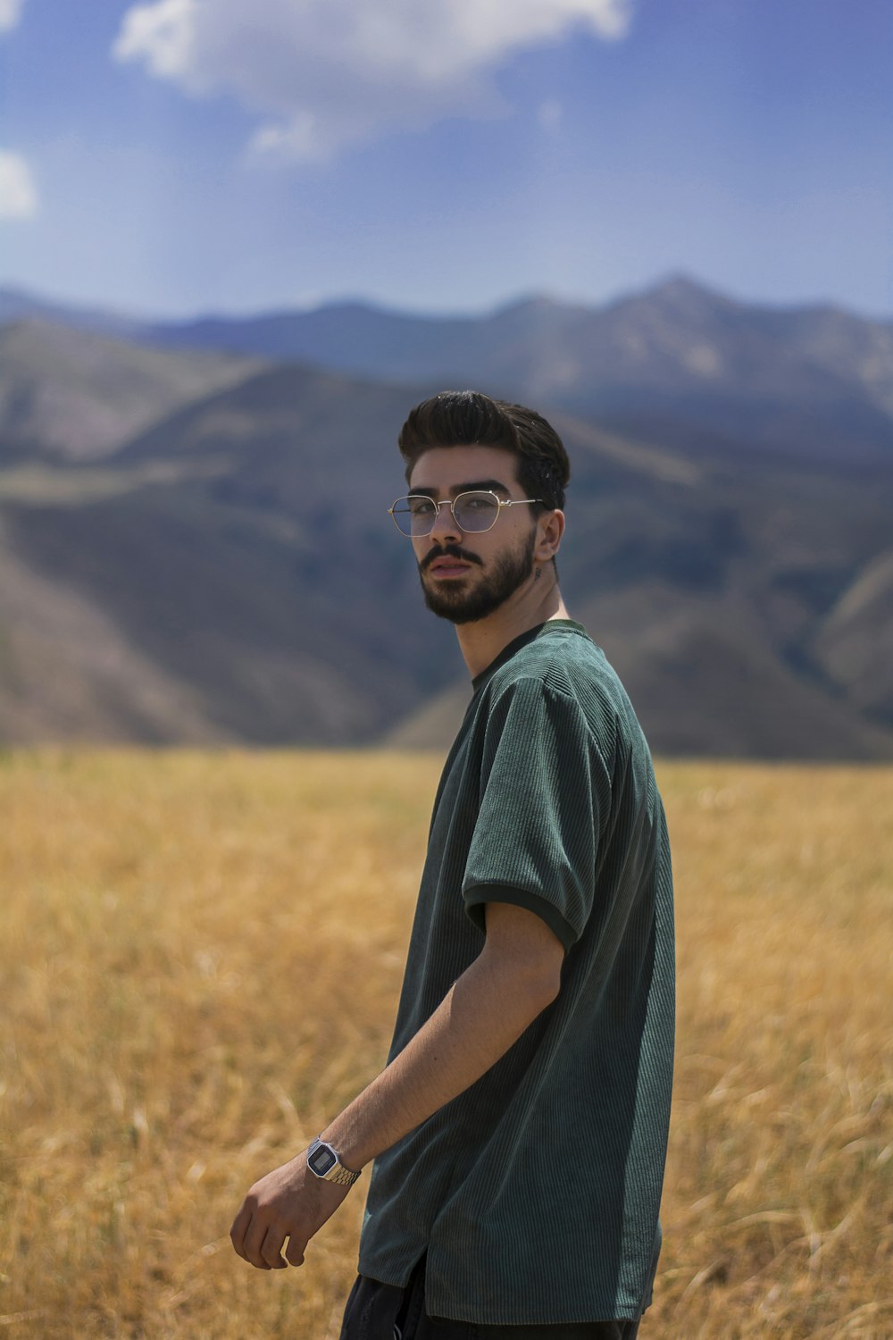 man in green crew neck t-shirt standing on brown grass field during daytime