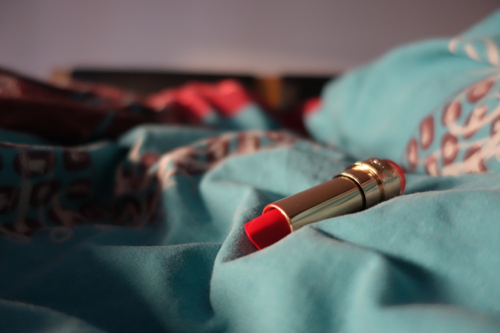 un rossetto rosso appoggiato su una coperta blu