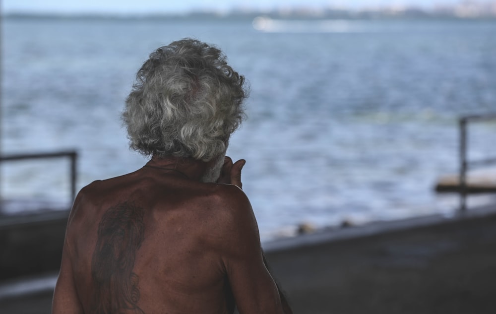 topless boy standing on beach during daytime