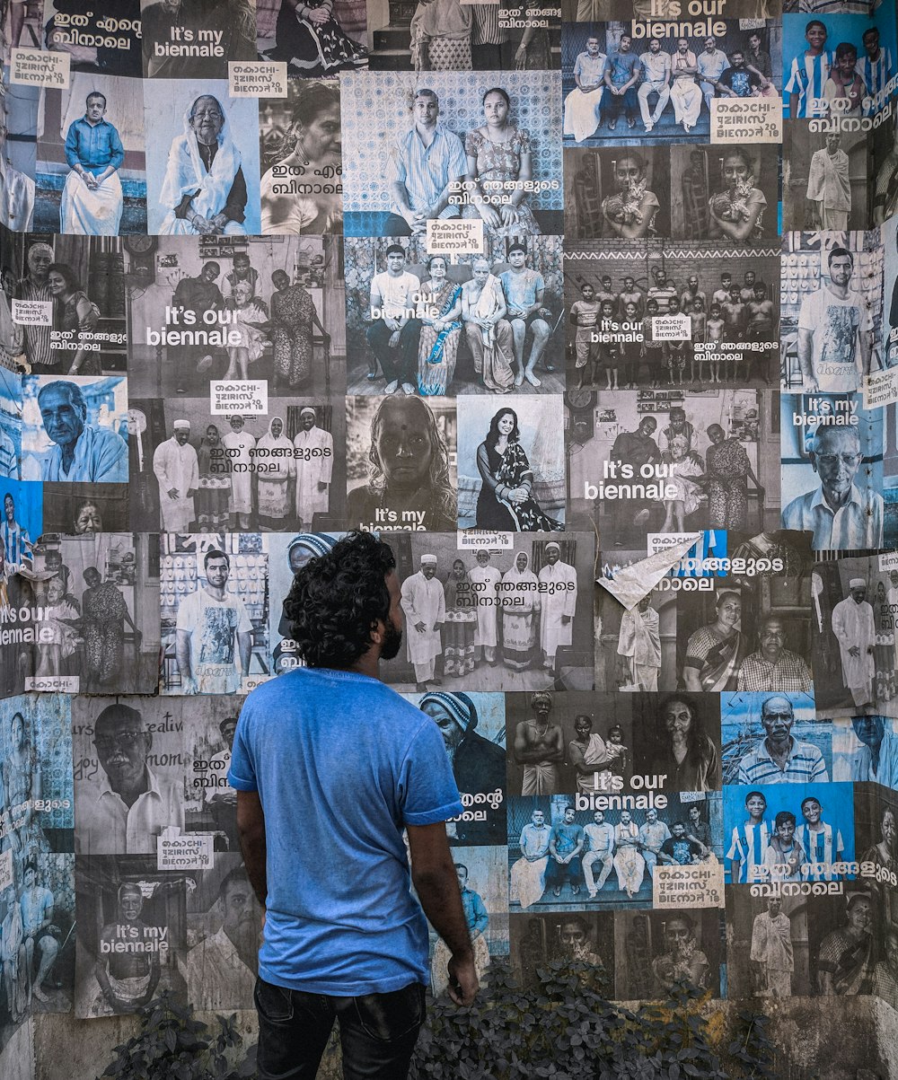 man in orange t-shirt standing in front of wall with posters