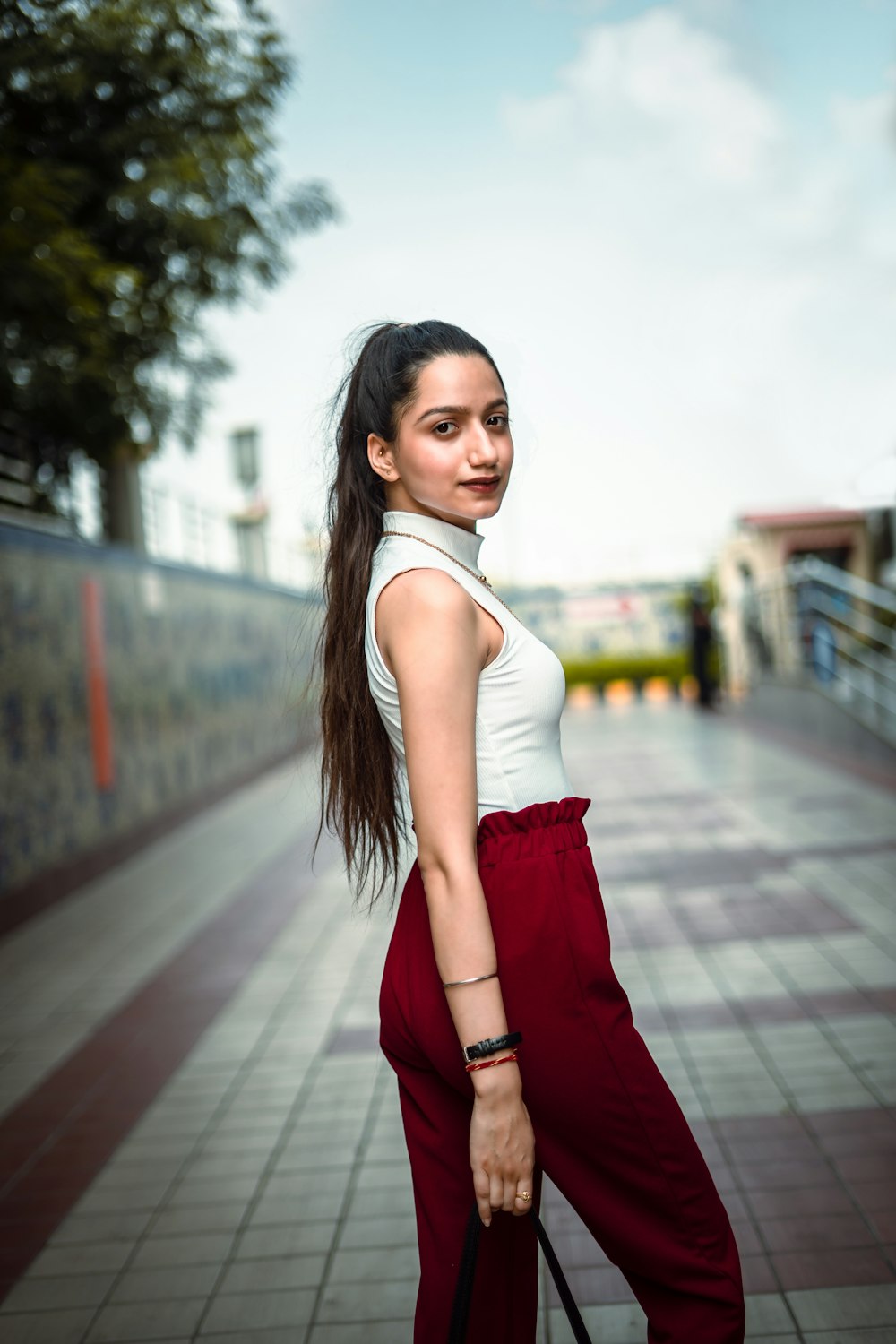 woman in white tank top and red skirt standing on sidewalk during daytime