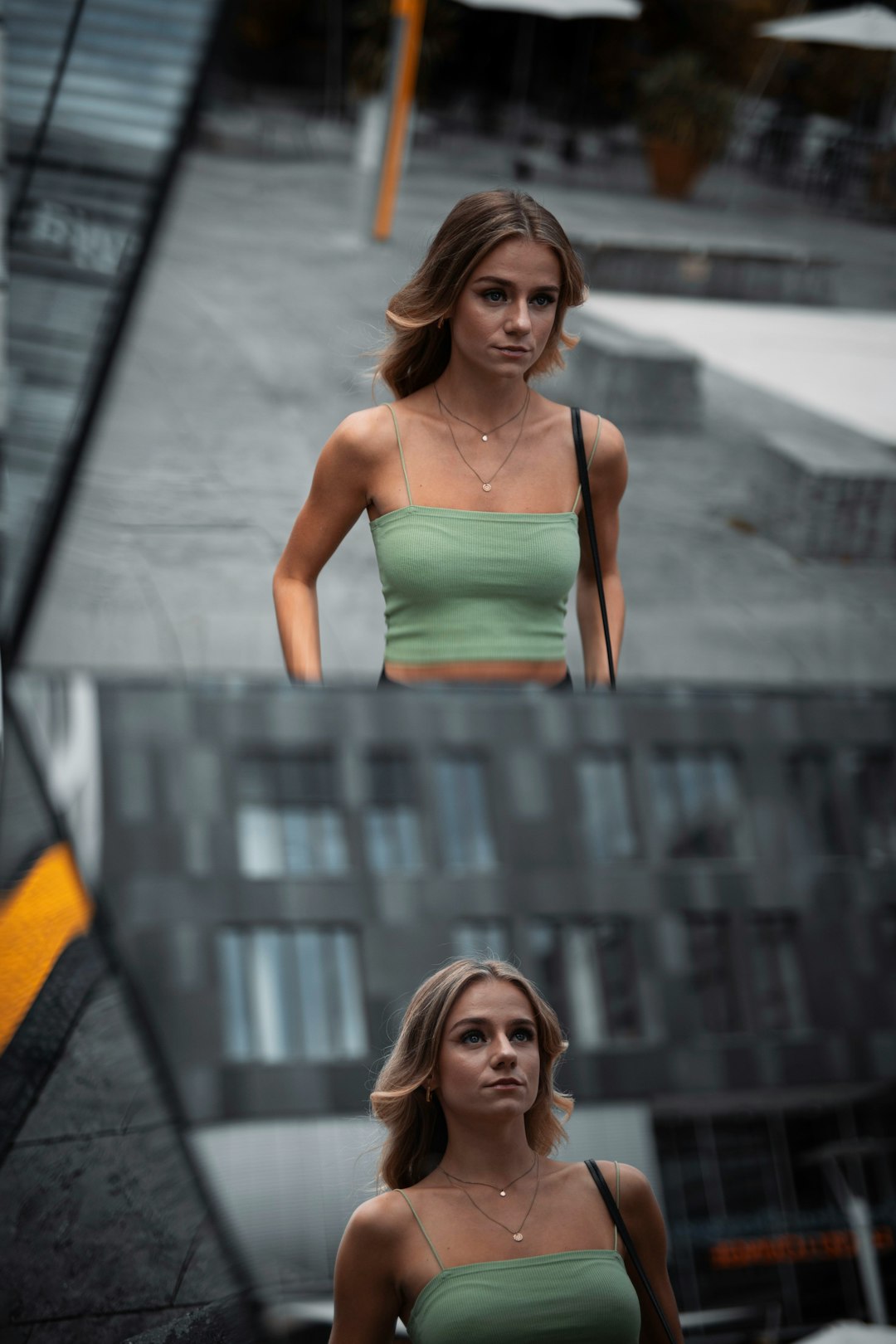 woman in green spaghetti strap top standing on gray concrete stairs