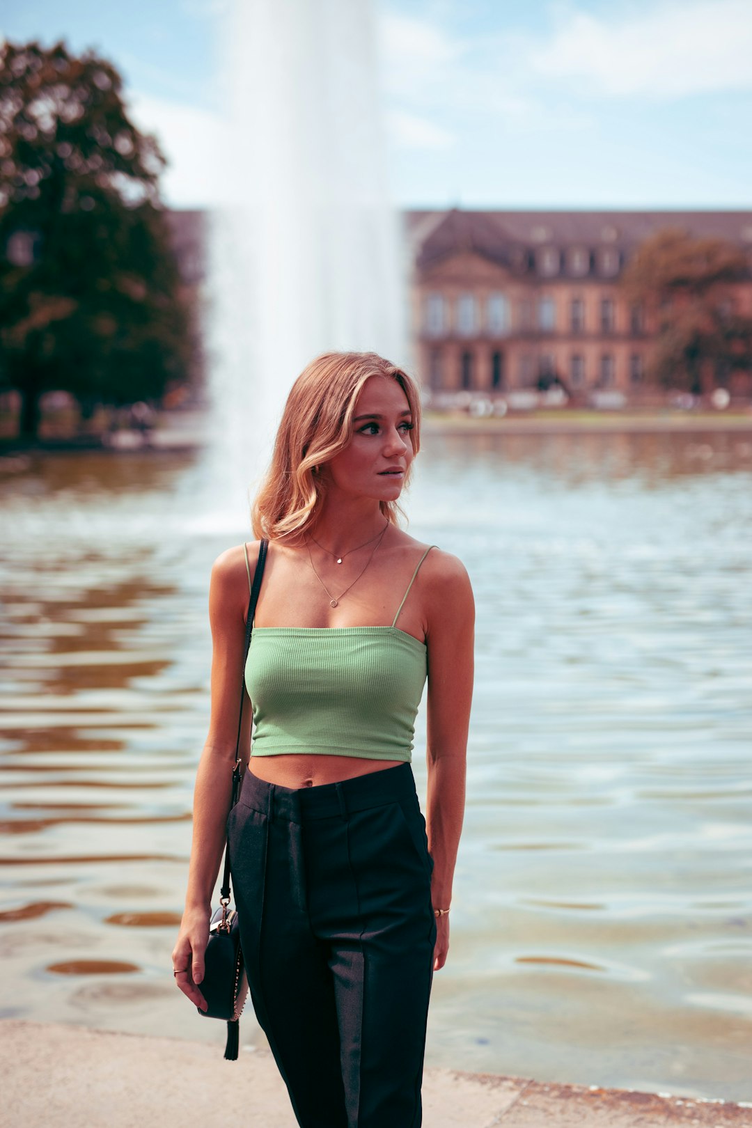 woman in green tank top and black pants standing on water during daytime