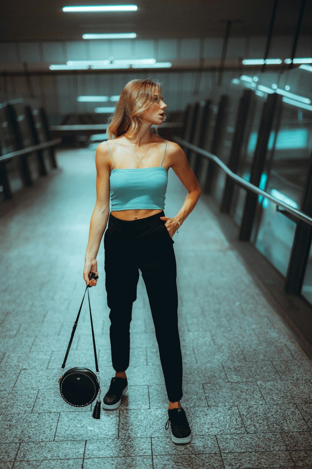 woman in white tank top and black pants standing on hallway