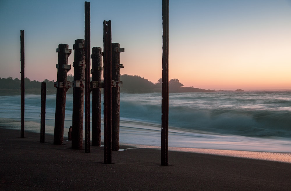 silhueta de posts na praia durante o pôr do sol