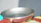 Close-up of a bronze pan with a warm patina resting on a rustic wooden countertop.