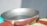 Close-up of a shiny metal skillet on a wooden countertop, steam rising gently.