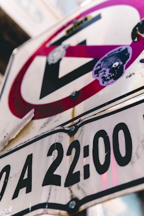 A close-up of a neighborhood street sign with a subtle shadow of a suspicious figure in the background.