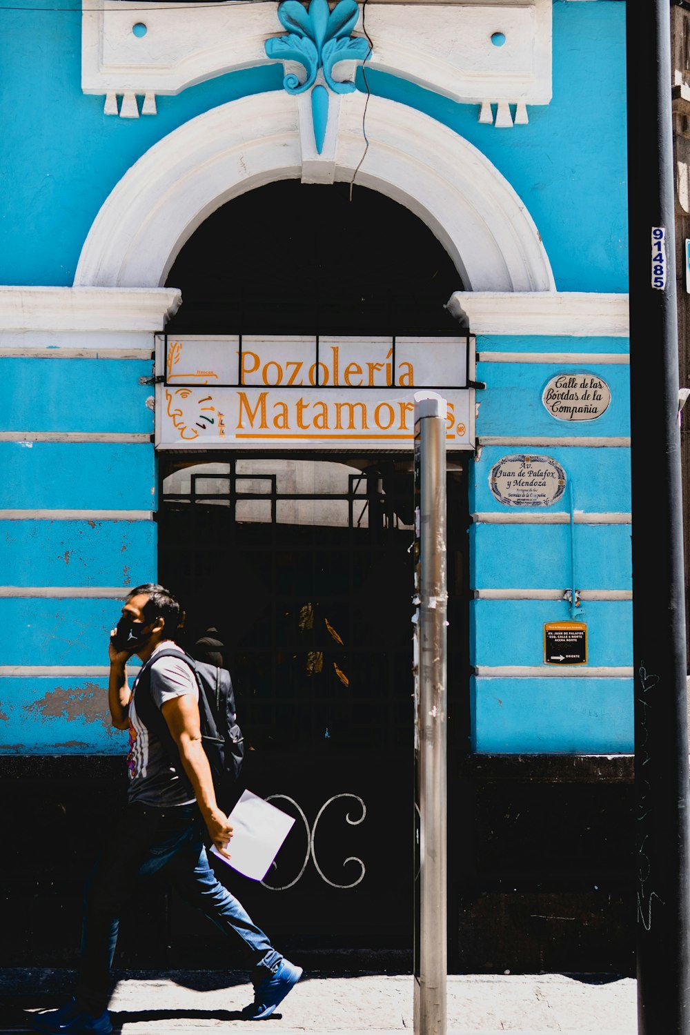 woman in black and white t-shirt and white shorts standing beside blue metal door during