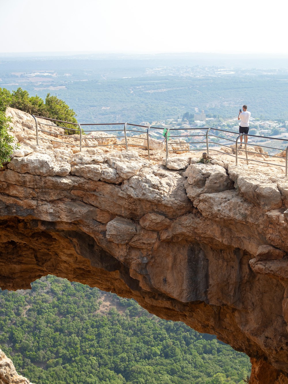 man in white shirt and black shorts standing on brown rock formation during daytime