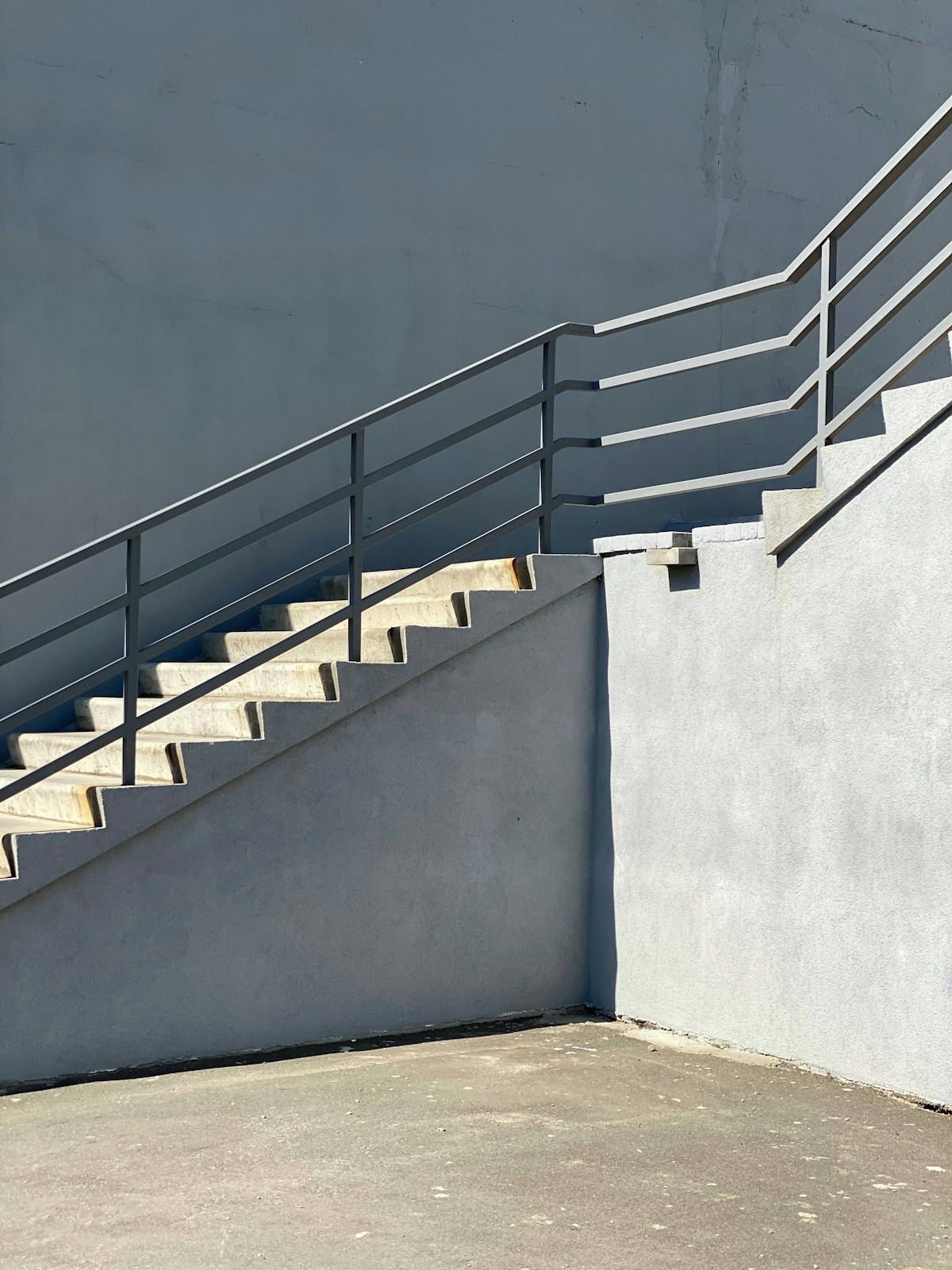 Steel catwalk stairway with perforated mesh guardrail panels in bright sunlight