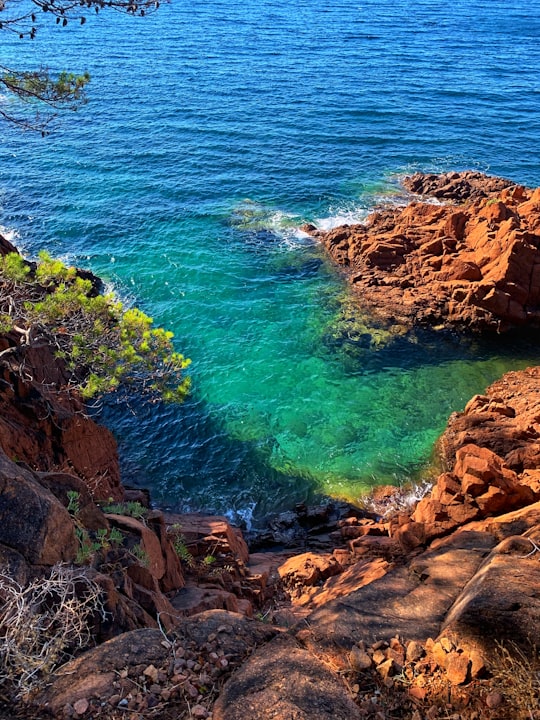 brown rock formation on body of water during daytime in Forêt Domaniale de l' Estérel France