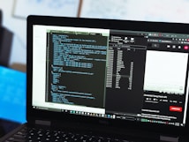 A laptop displaying a dual-screen setup with coding scripts on one side and a YouTube video on the other. The scripts are in a code editor, while the YouTube side shows a video tutorial about using the Fetch API in JavaScript. There are multiple tabs open, and a file explorer is visible.