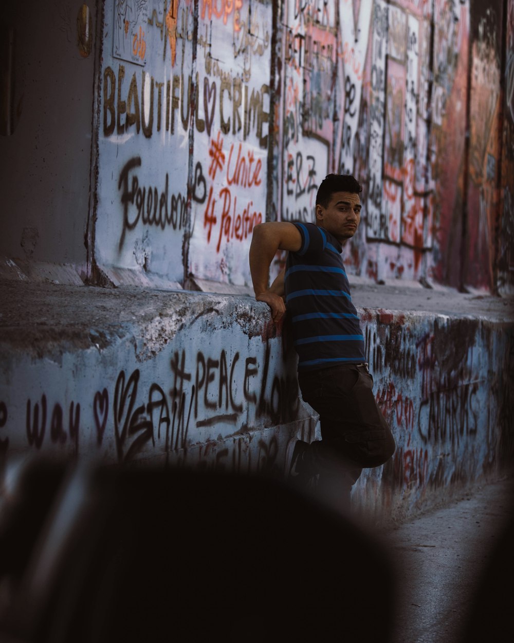 a man leaning against a wall covered in graffiti