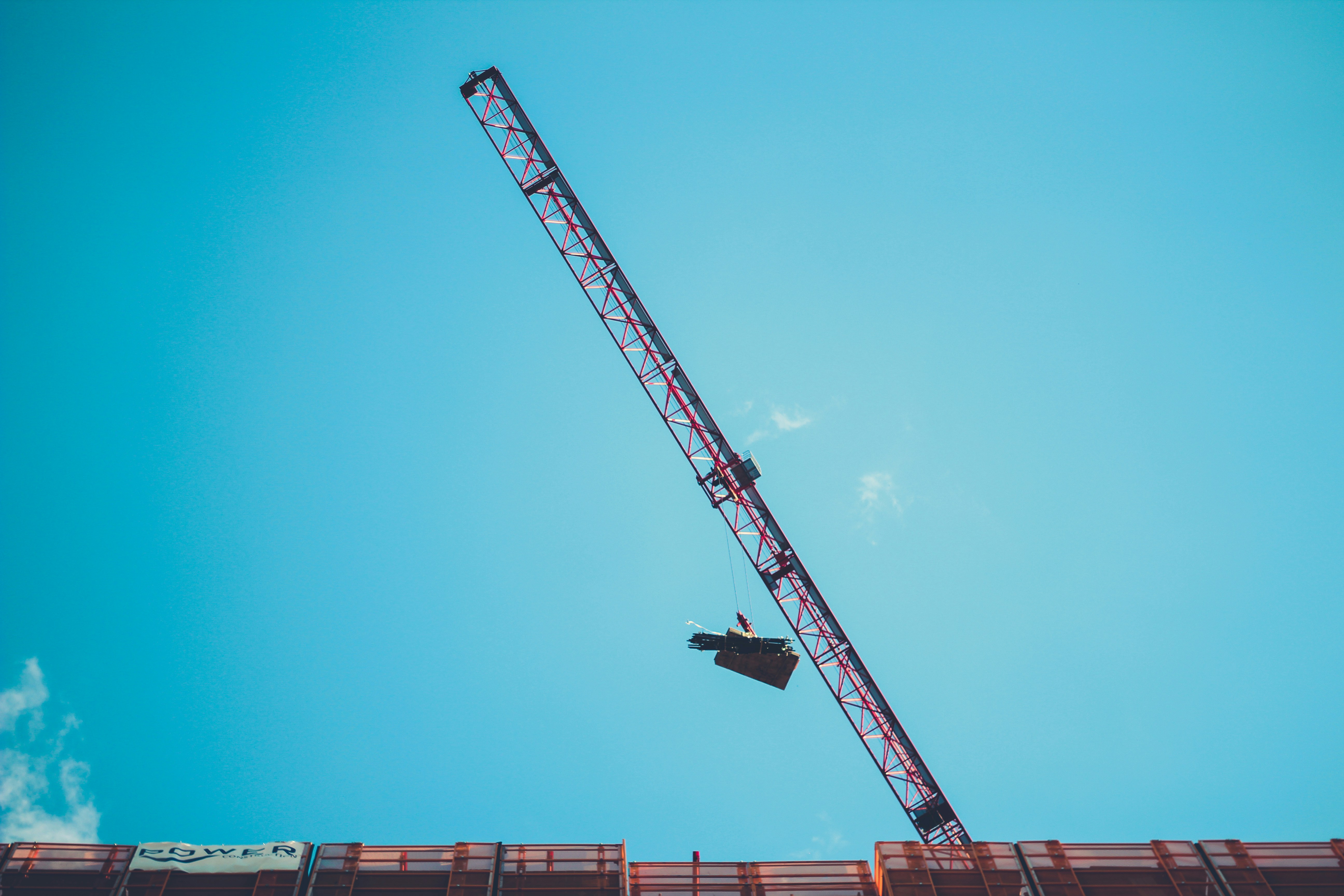 red and white crane under blue sky during daytime