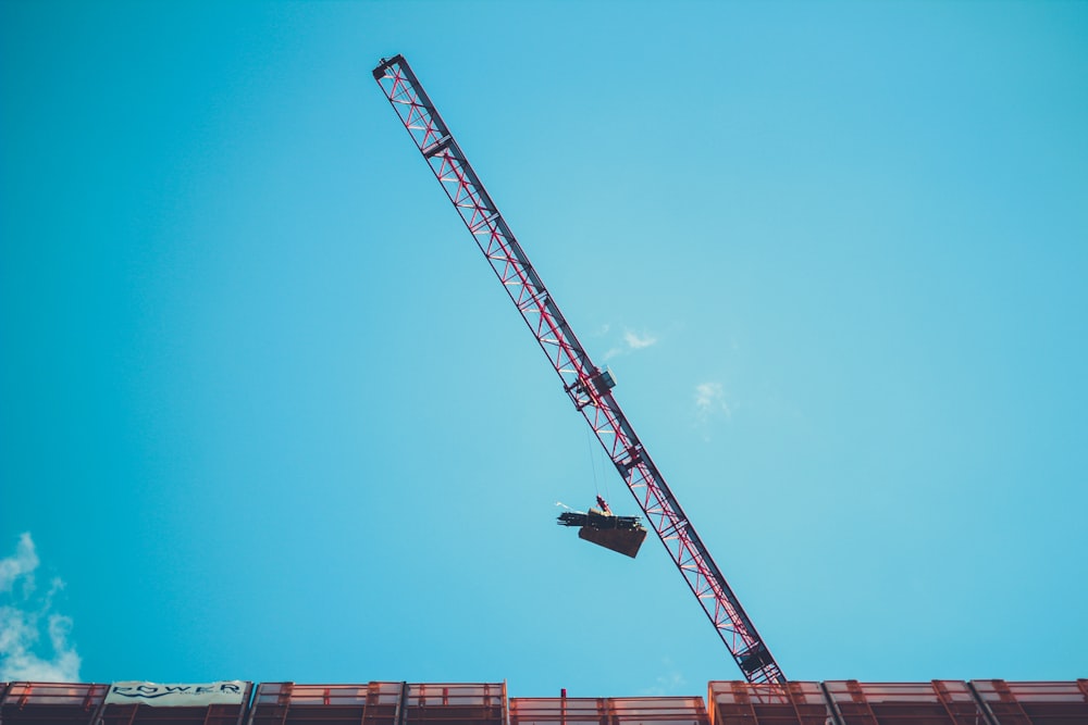 red and white crane under blue sky during daytime