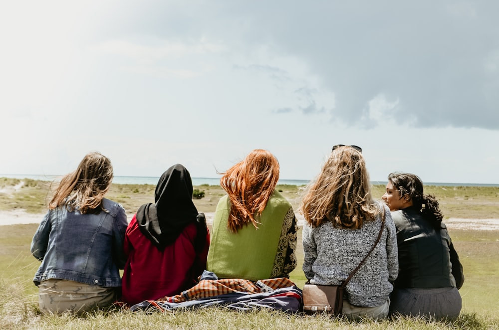 group of people sitting on grass field during daytime