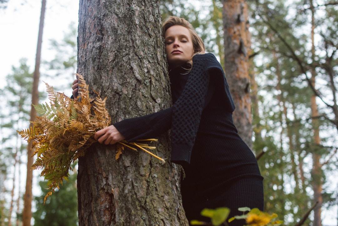 woman in black jacket and black pants sitting on tree