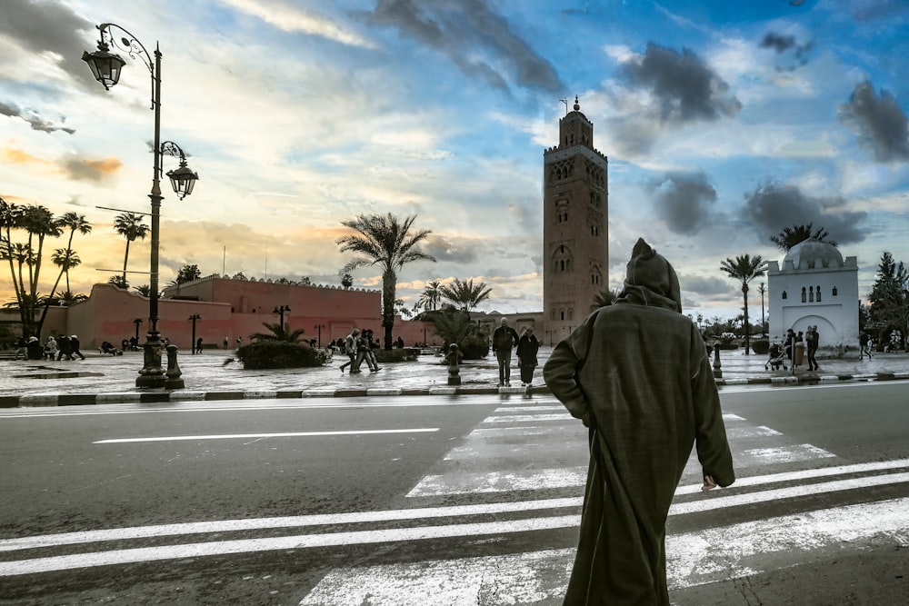 man in gray robe standing on road during daytime