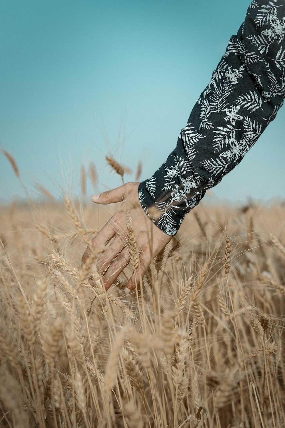 person in black and white floral long sleeve shirt standing on brown grass field during daytime