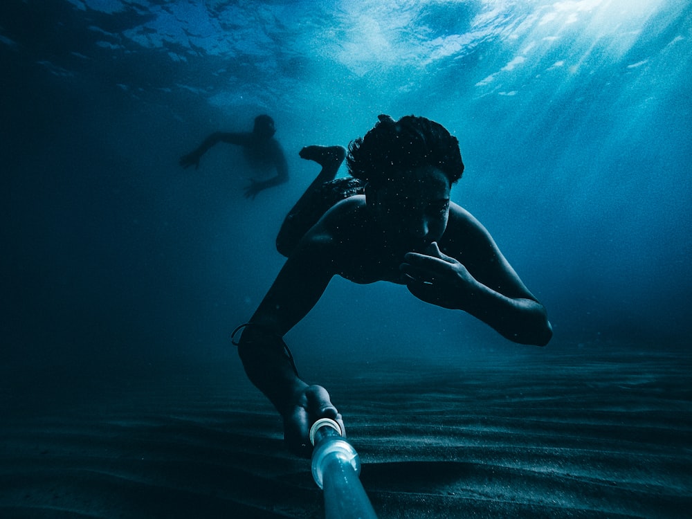 Hombre en pantalones cortos negros bajo el agua