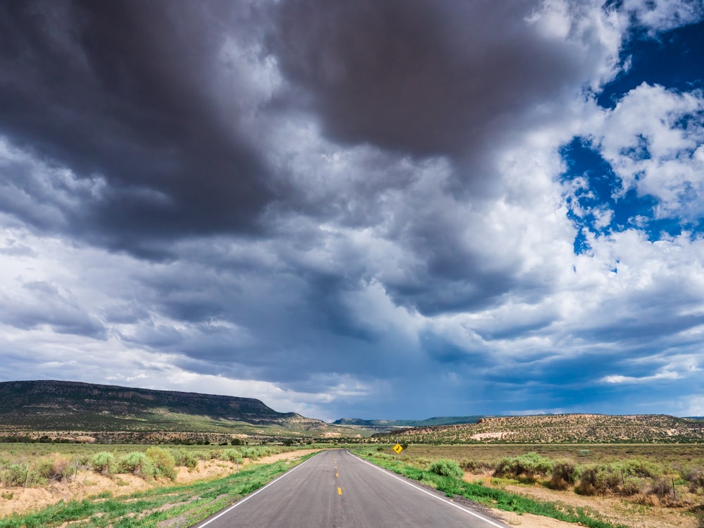 gray asphalt road under white clouds and blue sky during daytime