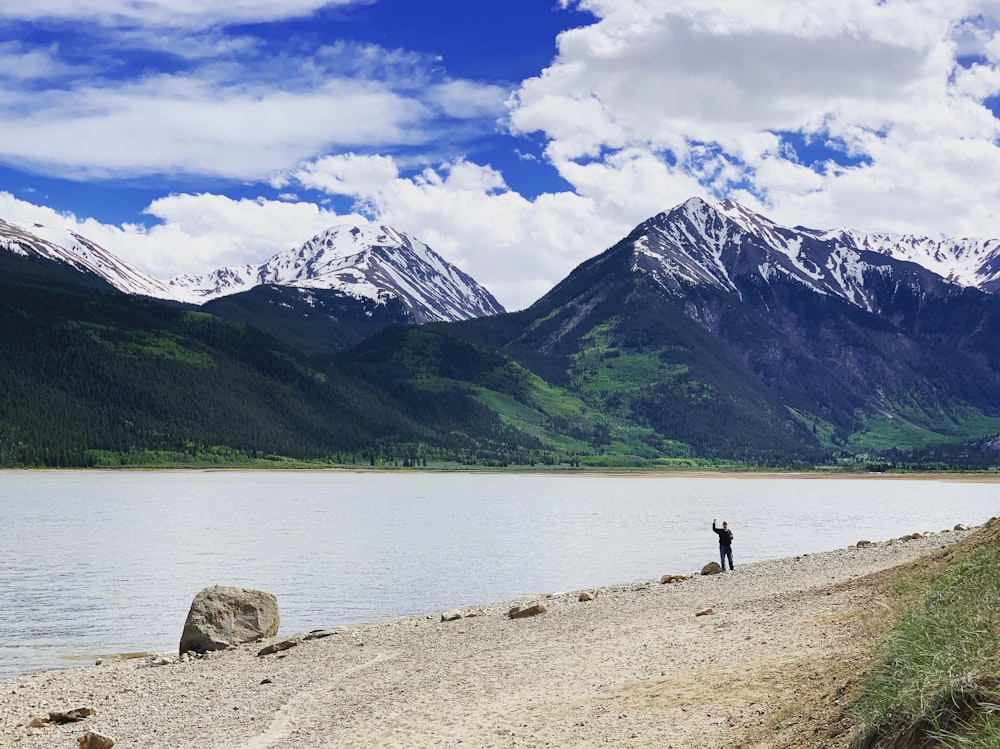 person standing on brown rock near lake during daytime