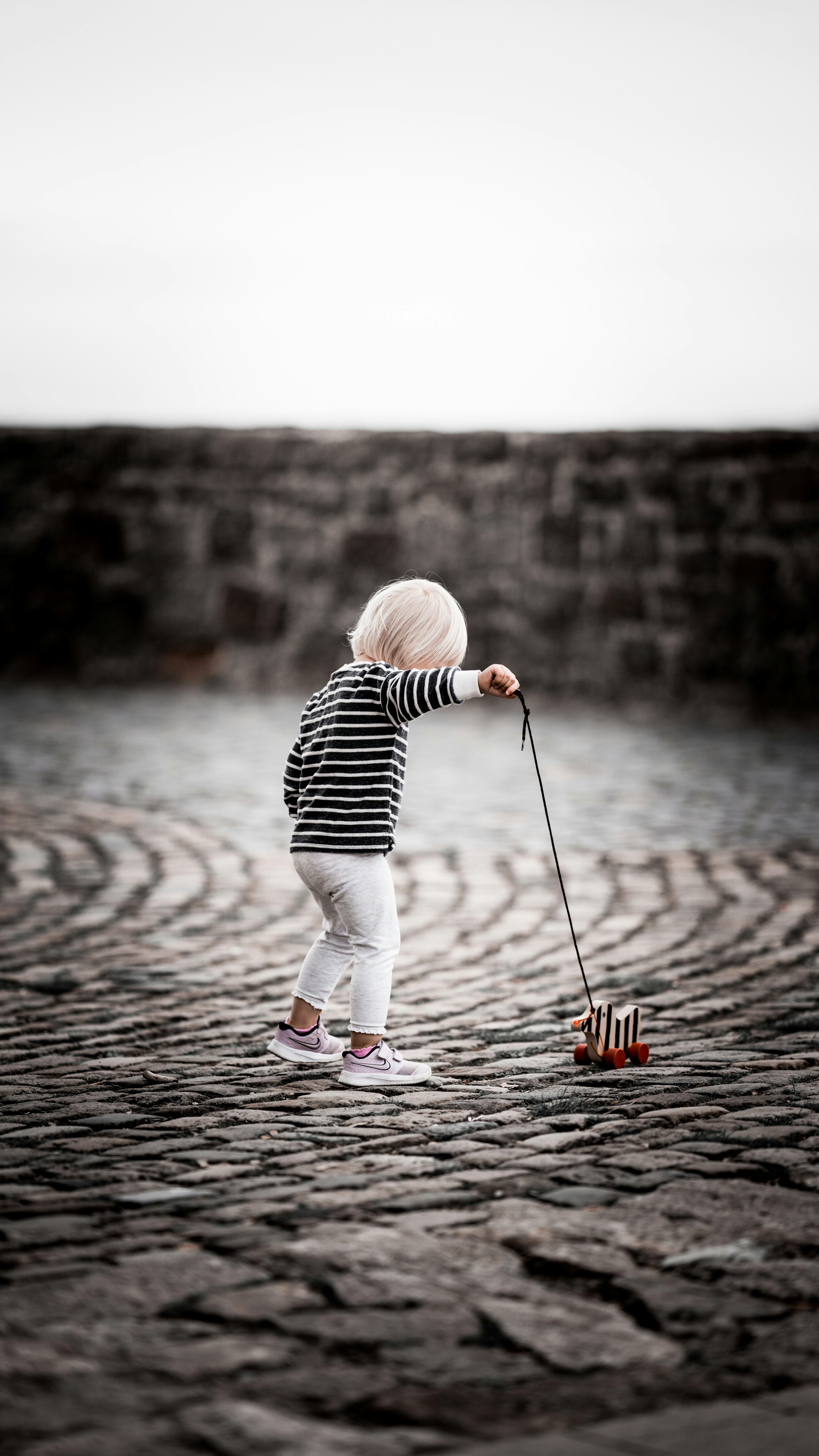 child in black and white striped long sleeve shirt and white pants standing on brown wooden